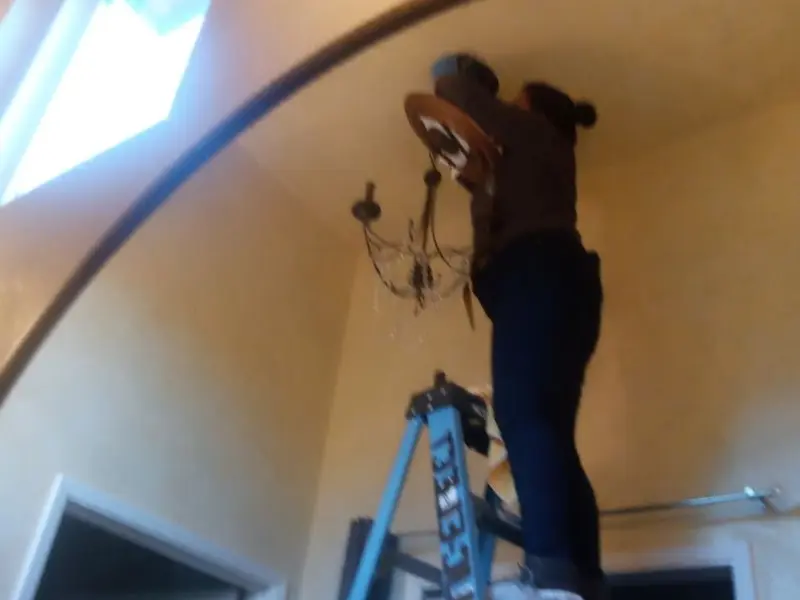 Electrician installing a chandelier in a Baltimore residence